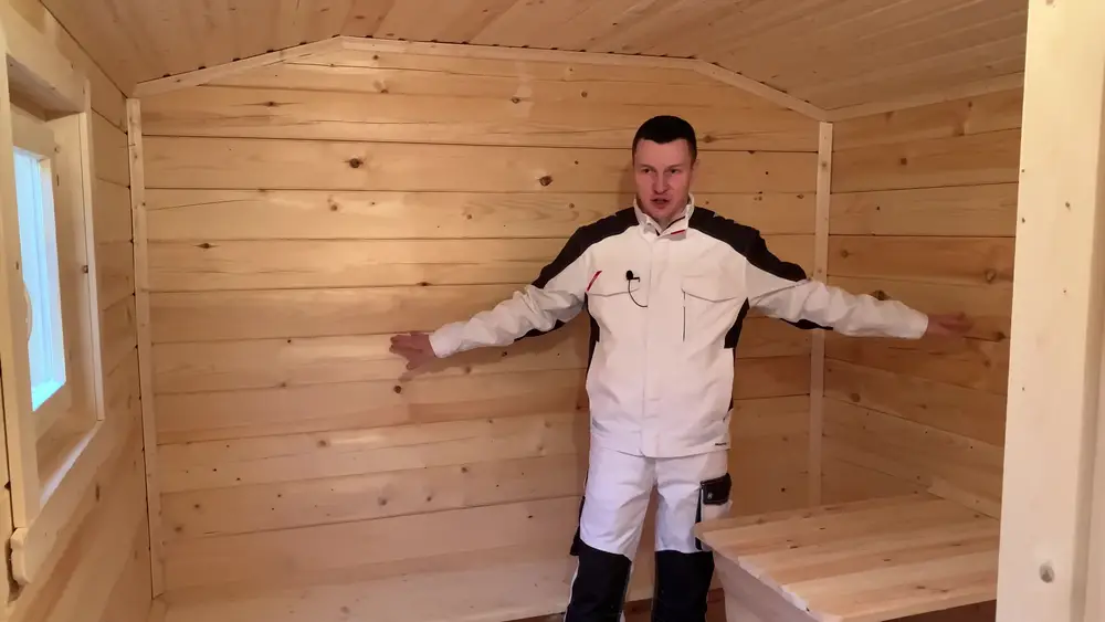 Комната отдыха мобильной бани с лавками вдоль стен и столиком
