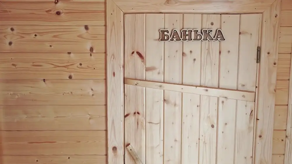 Резная табличка «Банька» над дверью в парилку мобильной бани
