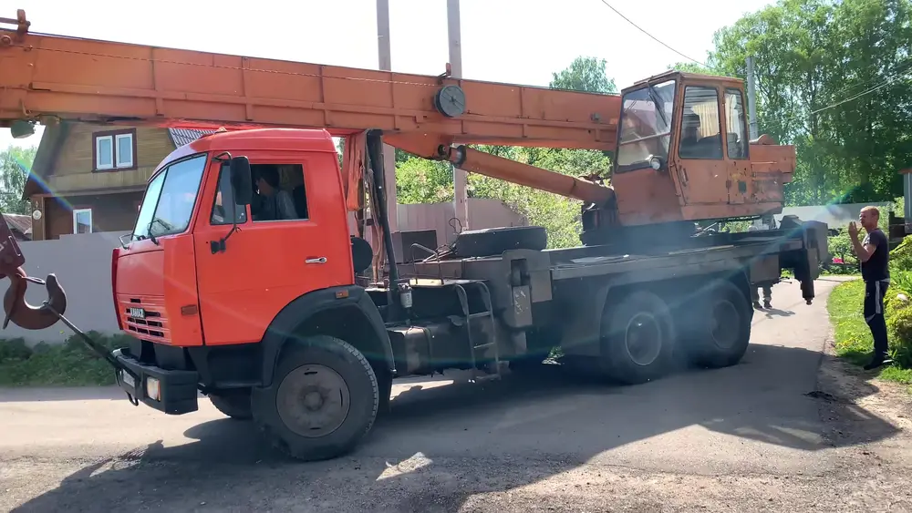 Автокран на базе КамАЗа с длинной стрелой и грузоподъёмностью 25 тонн встал на узкой улице рядом с участком в Парголово