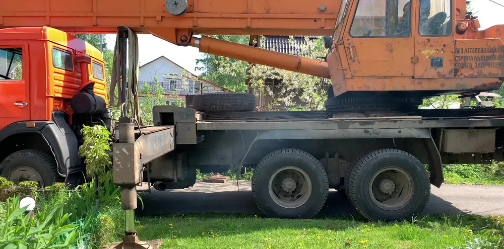 Выдвижная опора автокрана упёрта в землю рядом с бортом машины, лапа занимает около метра пространства сбоку