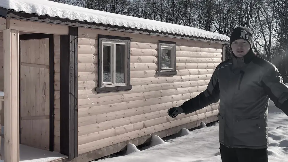 Стена бани из бруса 140 на 140 мм со светло-коричневой покраской и оконными наличниками