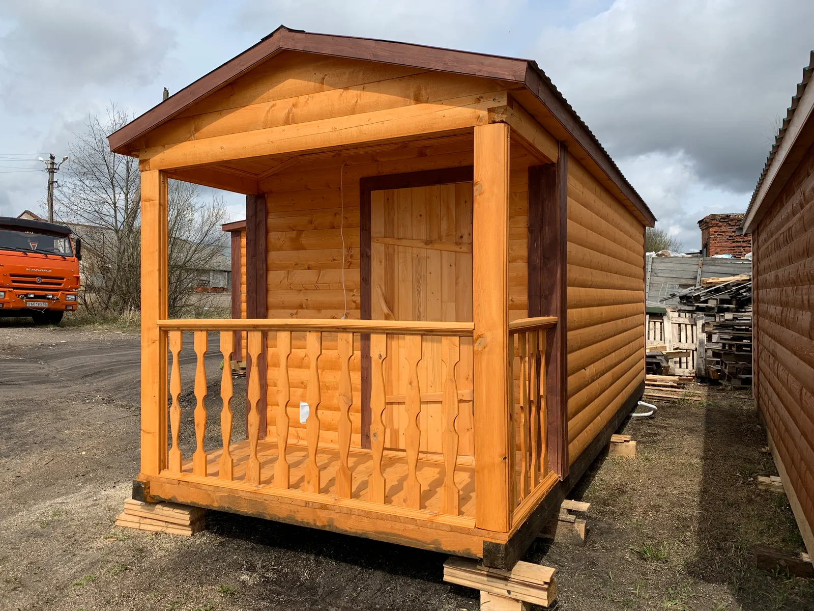 Торцевой вид бани 2,3×6 с крыльцом — резные балясины, входная дверь