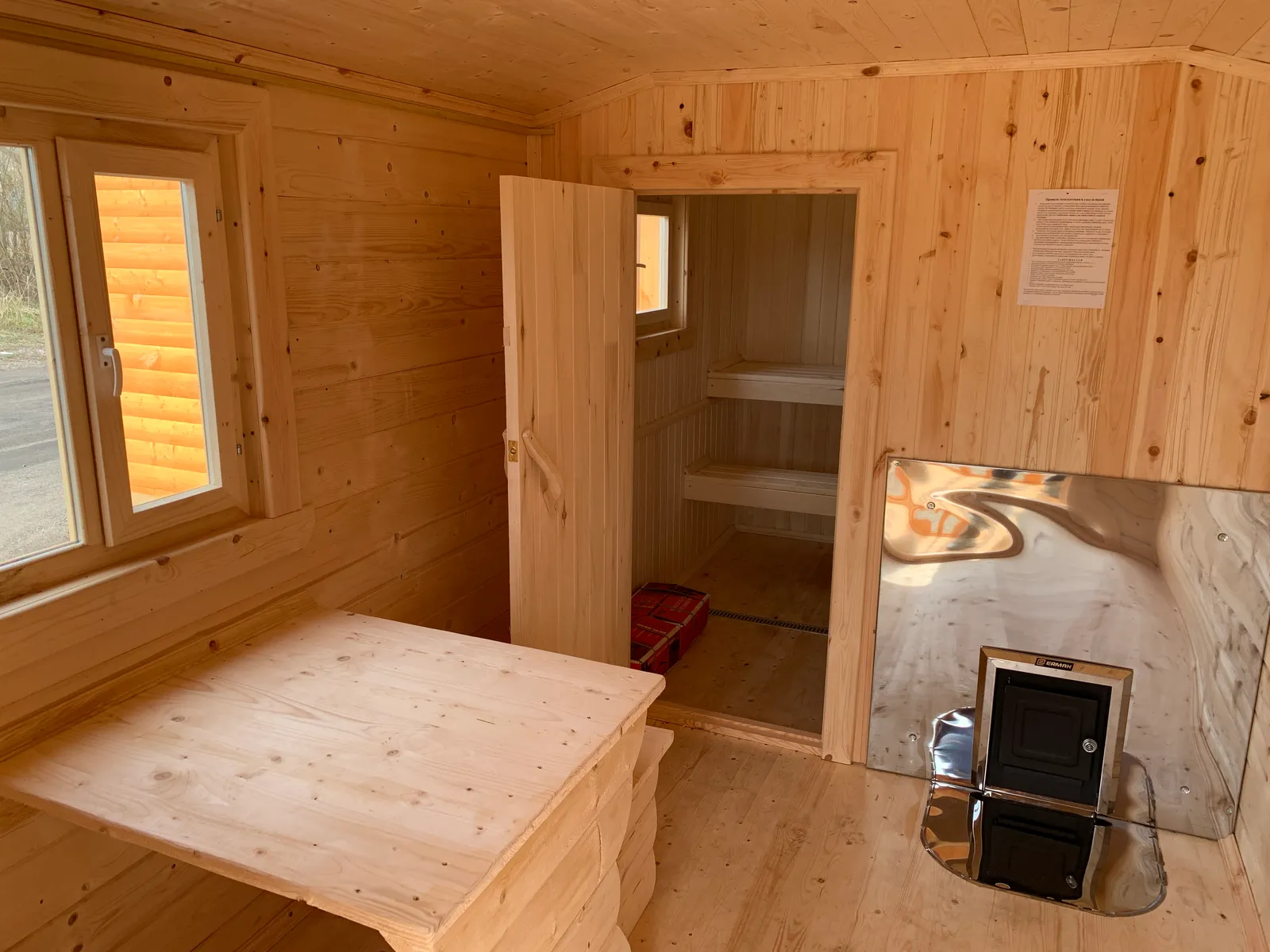 Комната отдыха бани 2,3×6 — печь с выносной топкой, вид на дверь в парилку