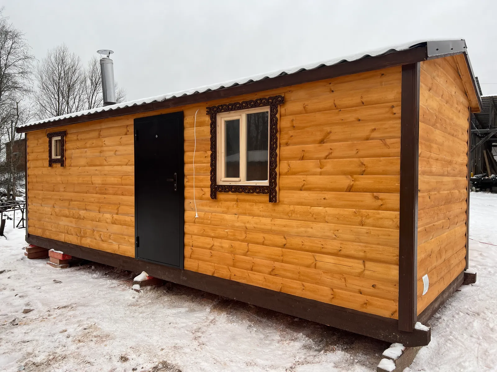 Баня из бруса 2,3×7 зимой — боковой фасад, окна с резными наличниками