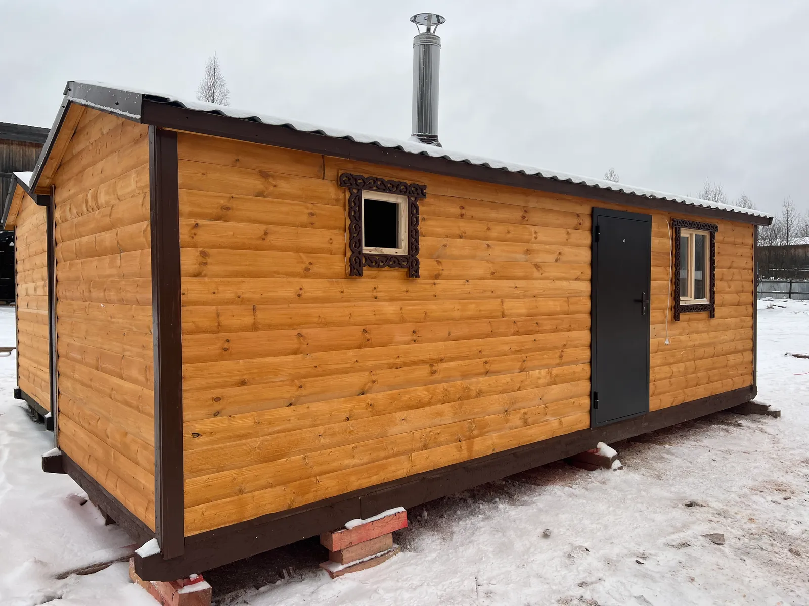 Задний фасад бани 2,3×7 — окно с резным наличником, металлическая дверь, дымоход