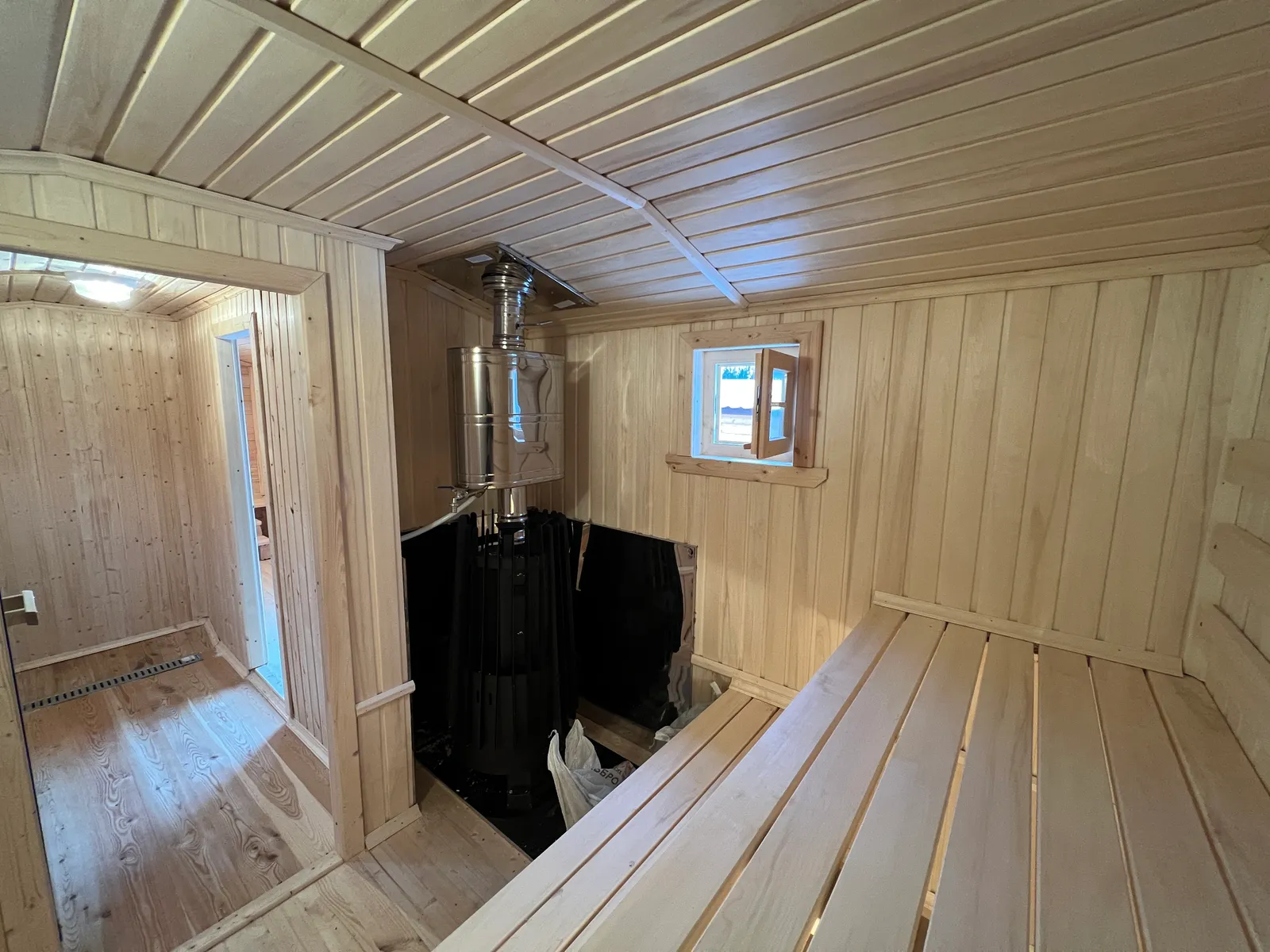 Печь-каменка в парилке бани 2,3×7 — вид через дверной проём из моечной