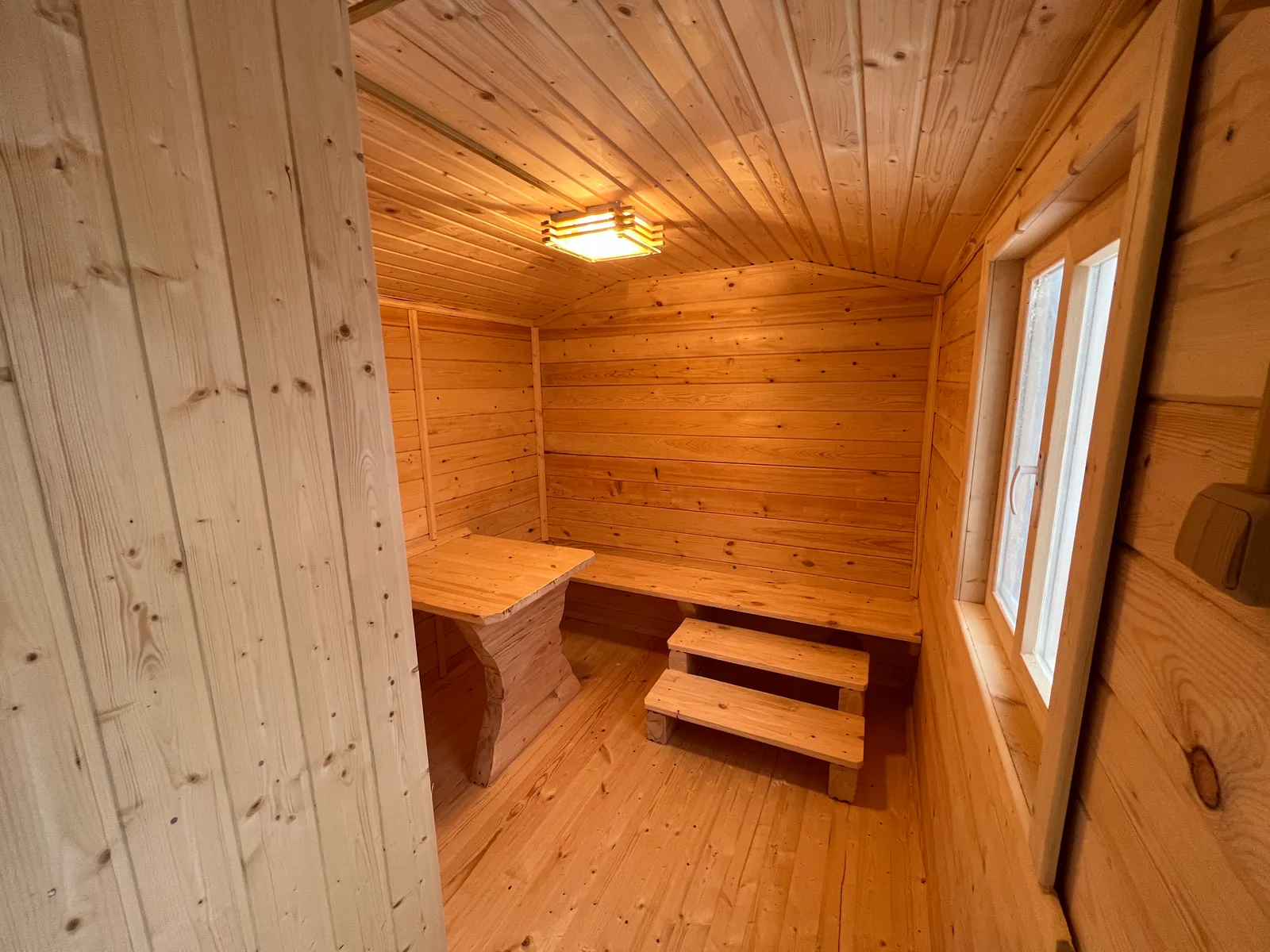 Комната отдыха бани 2,3×7 — лавки и столик, потолочный светильник, тёплое освещение